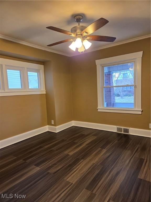 spare room featuring ornamental molding, visible vents, baseboards, and dark wood-style floors