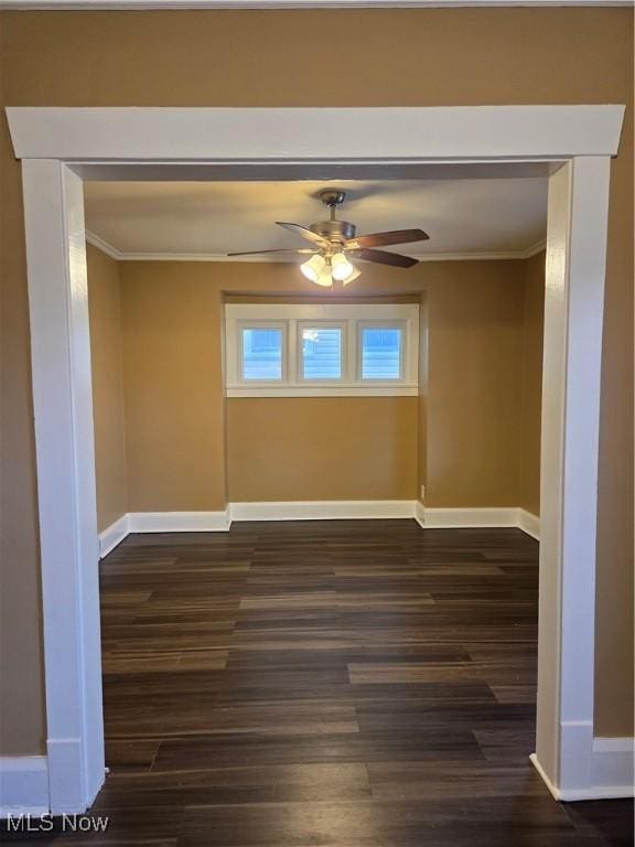 empty room with baseboards, dark wood finished floors, and crown molding