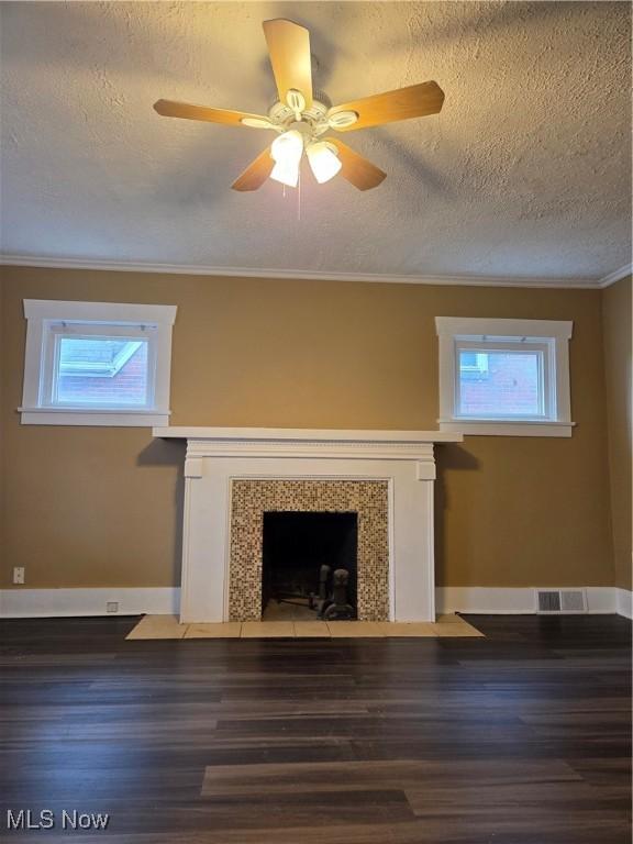 unfurnished living room with ornamental molding, wood finished floors, a fireplace with flush hearth, and a wealth of natural light