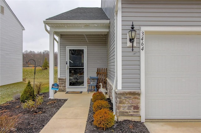 doorway to property featuring stone siding, a shingled roof, and an attached garage