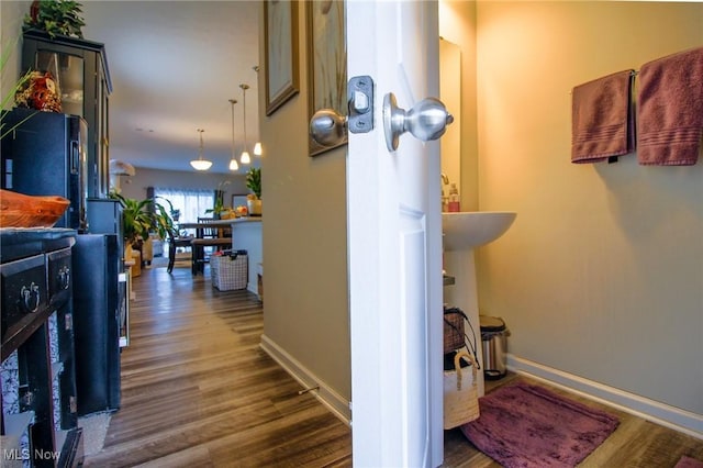 hall featuring dark wood-style flooring and baseboards