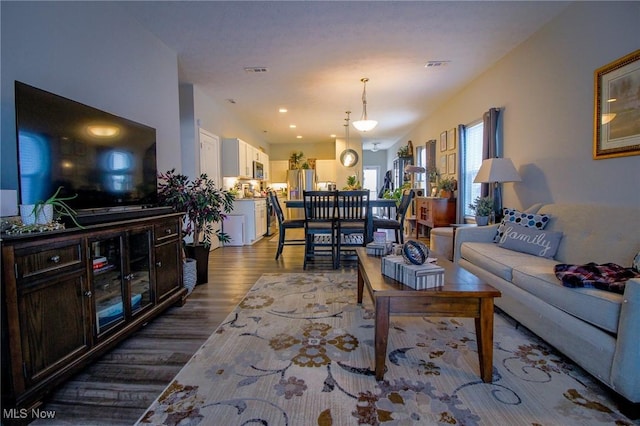 living room with recessed lighting, visible vents, and wood finished floors