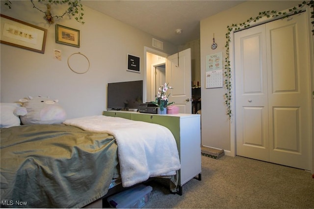 carpeted bedroom with a closet, visible vents, and baseboards