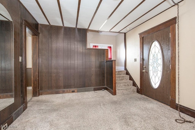 foyer featuring stairway, carpet floors, and wood walls