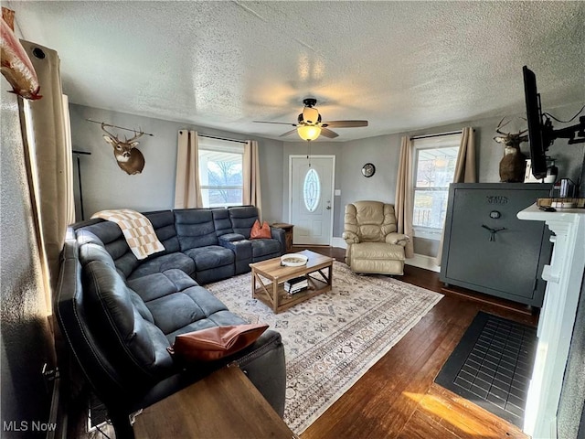 living area with baseboards, a textured ceiling, a ceiling fan, and wood finished floors