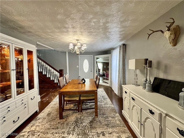 dining room featuring a chandelier, dark wood finished floors, stairway, and a textured ceiling