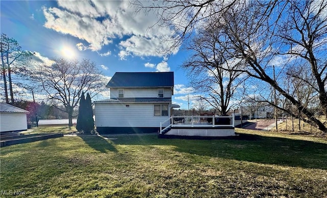 back of house with metal roof, a deck, and a lawn