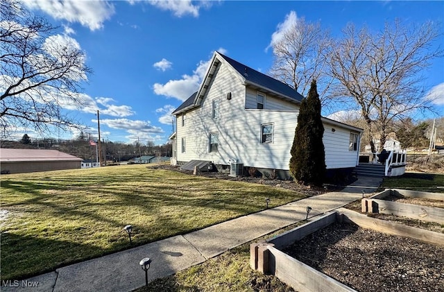 view of side of property featuring a garden, central AC, and a lawn