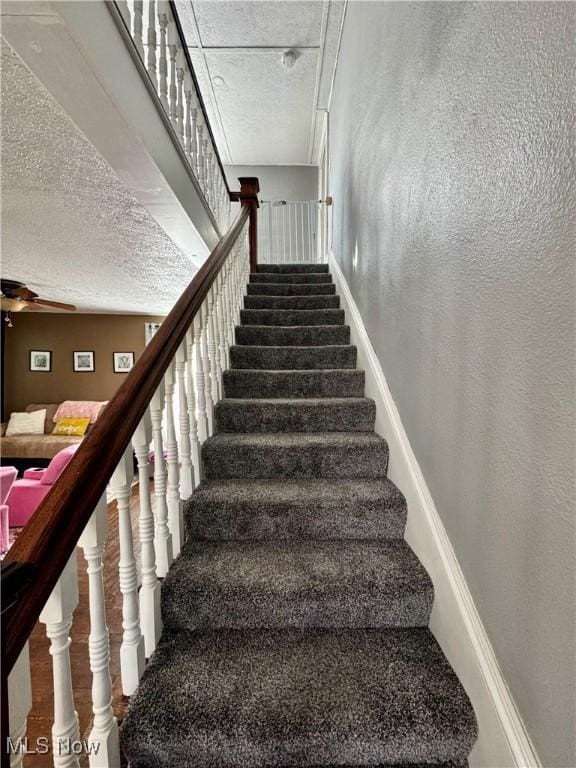 stairs featuring a textured ceiling and a textured wall