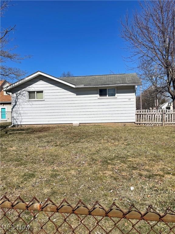 view of side of home with a yard and fence