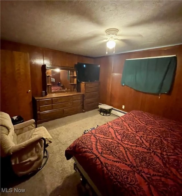 bedroom with baseboard heating, a ceiling fan, carpet flooring, wood walls, and a textured ceiling