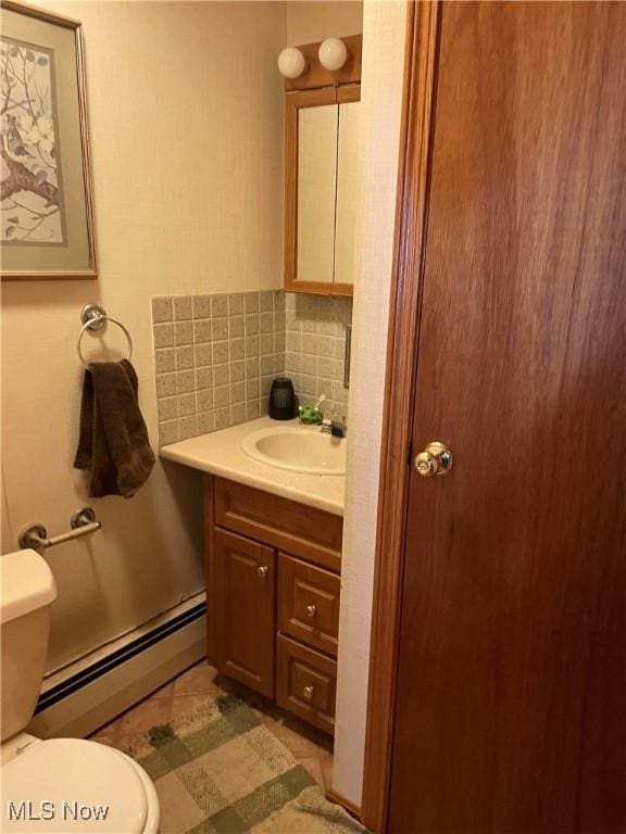 half bath featuring a baseboard heating unit, vanity, toilet, and decorative backsplash