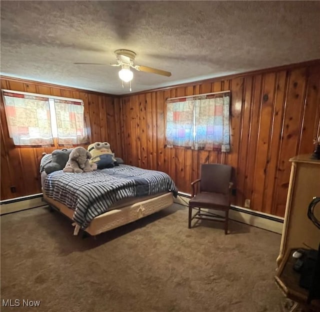 bedroom with a textured ceiling, carpet floors, baseboard heating, and wooden walls