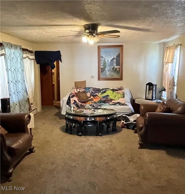 living area featuring a textured ceiling, carpet floors, and ceiling fan