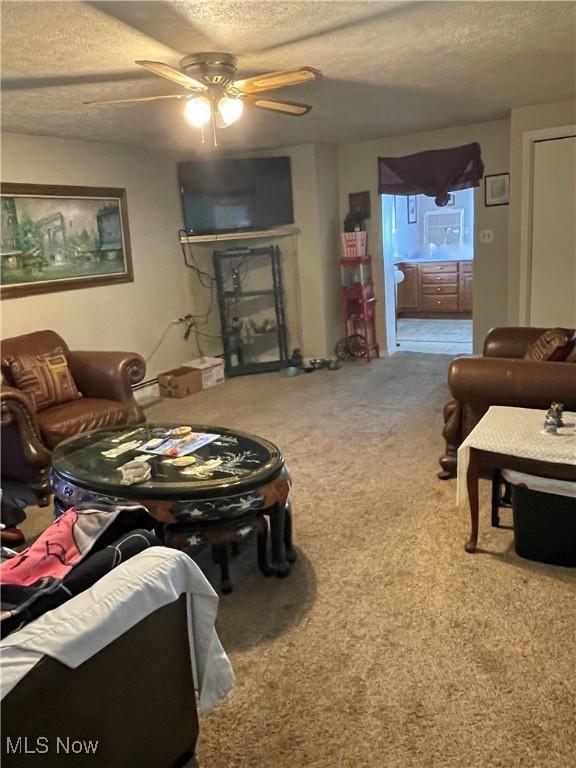 living room with carpet flooring, ceiling fan, and a textured ceiling