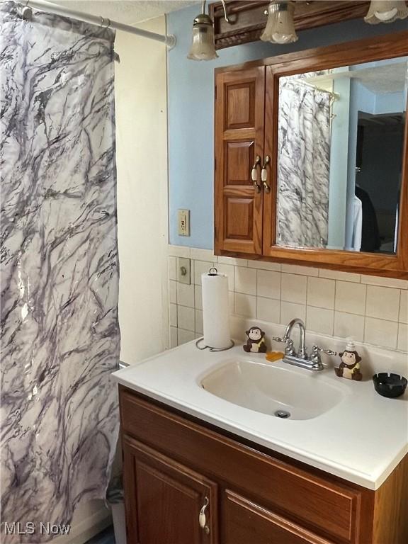 full bathroom with a shower with shower curtain, tile walls, and vanity