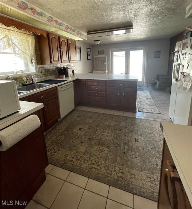 kitchen with light countertops, dishwasher, a sink, and light tile patterned floors