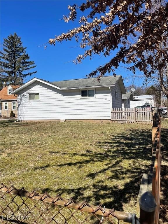 rear view of property with a yard and fence