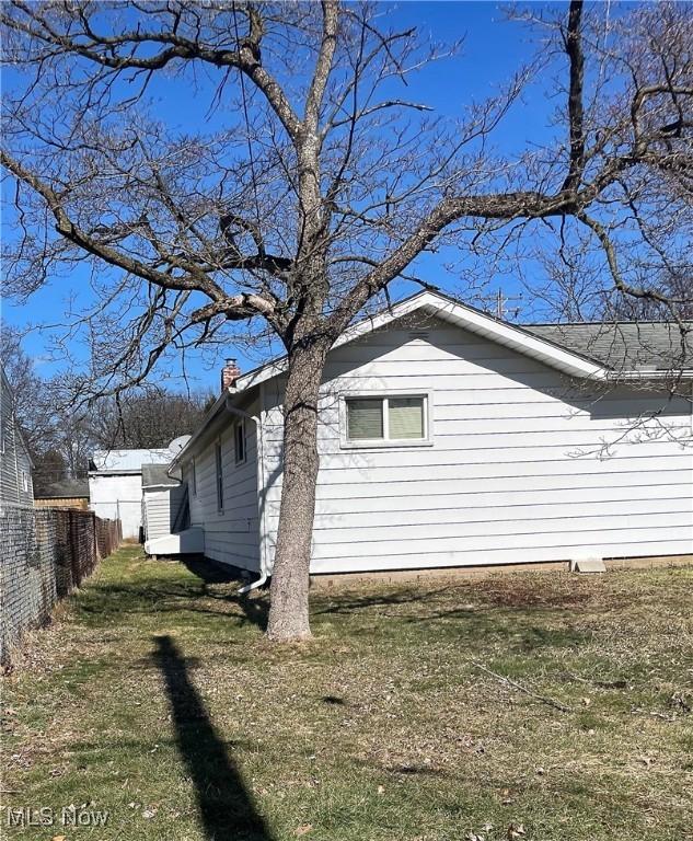 view of home's exterior with a yard, a chimney, and fence