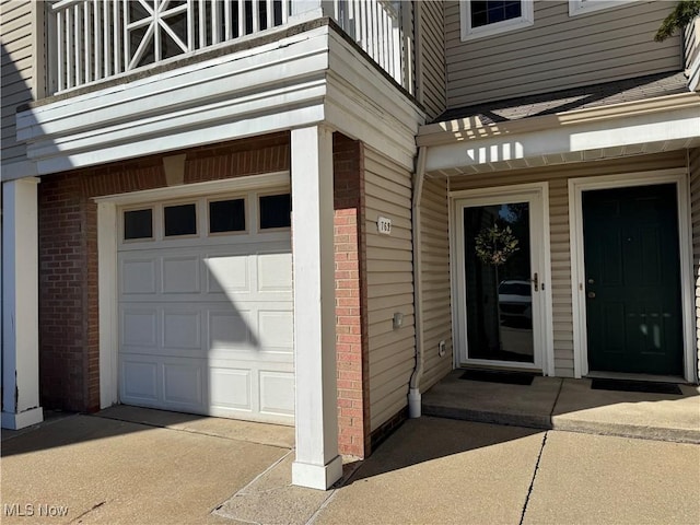 entrance to property featuring a balcony, a garage, and brick siding