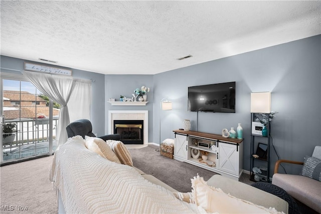 carpeted living area featuring a textured ceiling, baseboards, visible vents, and a tile fireplace