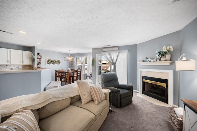 living area featuring visible vents, a textured ceiling, carpet floors, a fireplace, and baseboards