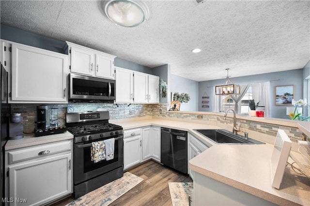 kitchen with a sink, wood finished floors, appliances with stainless steel finishes, white cabinets, and light countertops