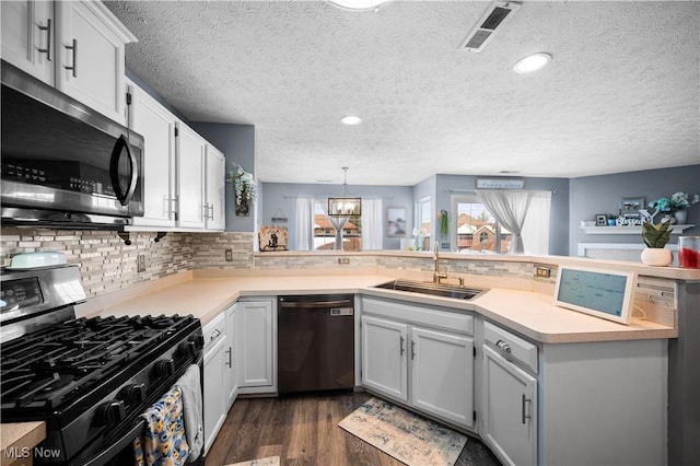 kitchen featuring visible vents, a peninsula, a sink, stainless steel appliances, and light countertops