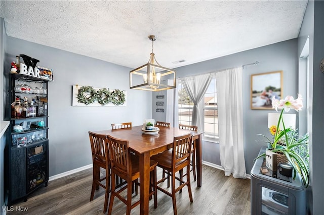 dining space with a textured ceiling, baseboards, and wood finished floors