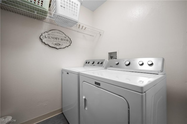 clothes washing area with baseboards, separate washer and dryer, and laundry area