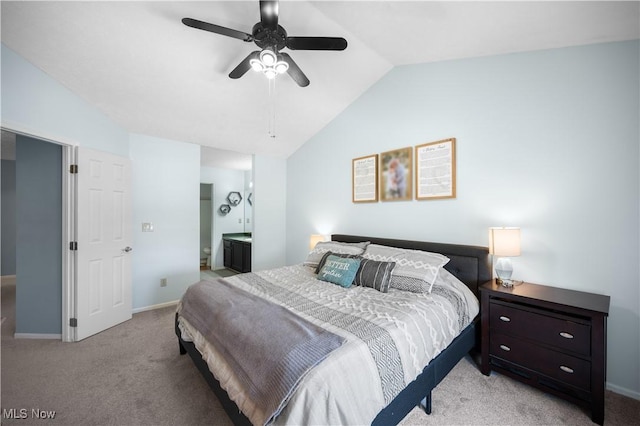 bedroom with baseboards, light colored carpet, ensuite bathroom, and vaulted ceiling