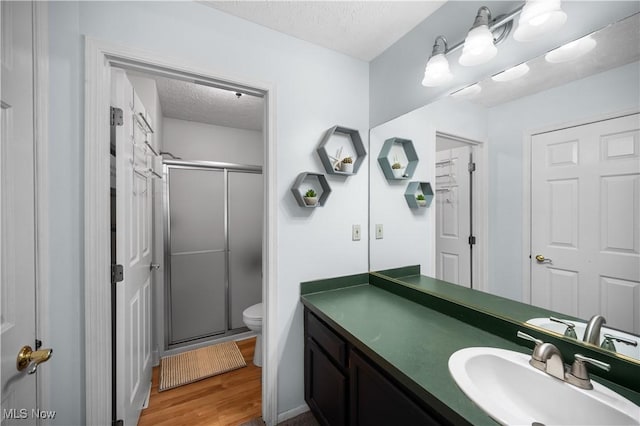 full bathroom featuring vanity, a textured ceiling, a shower stall, and toilet