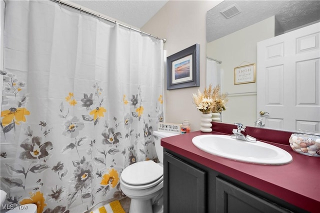 full bathroom with vanity, toilet, visible vents, and a textured ceiling