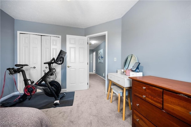 exercise room with baseboards, carpet floors, and a textured ceiling