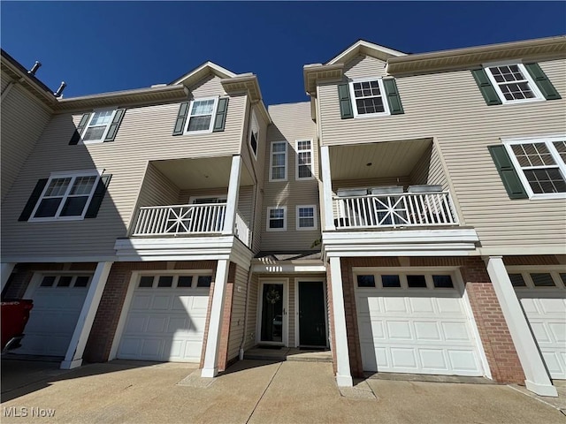 townhome / multi-family property featuring brick siding, a garage, and driveway