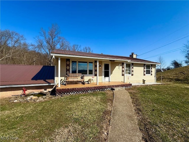 single story home featuring metal roof, a porch, a front yard, a standing seam roof, and a chimney