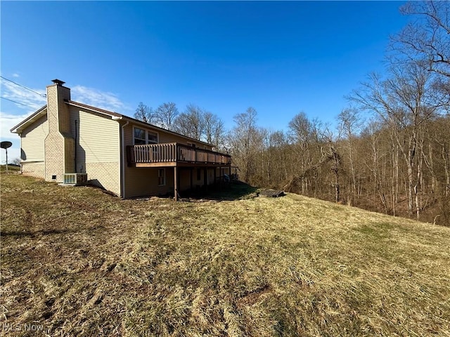 view of home's exterior with a deck, a chimney, and a lawn