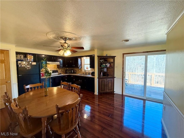 dining room with a wainscoted wall, a textured ceiling, visible vents, and dark wood-type flooring