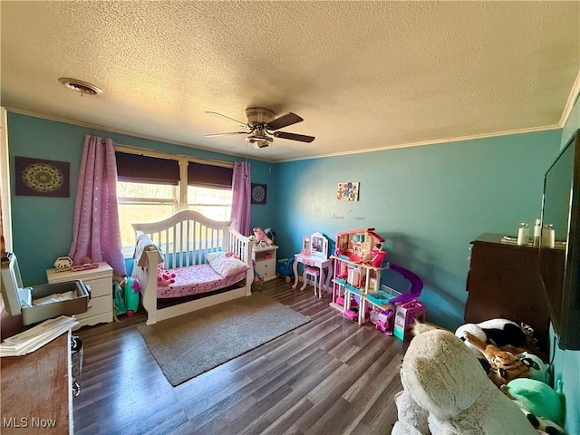 bedroom with ceiling fan, a textured ceiling, wood finished floors, visible vents, and ornamental molding