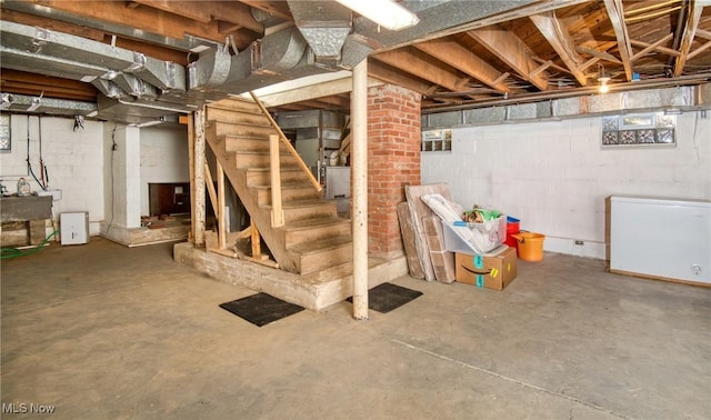 unfinished below grade area with a sink, stairway, and fridge