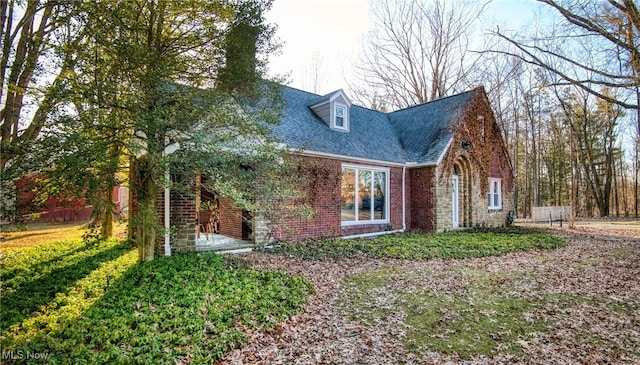 view of front of home with brick siding and a shingled roof