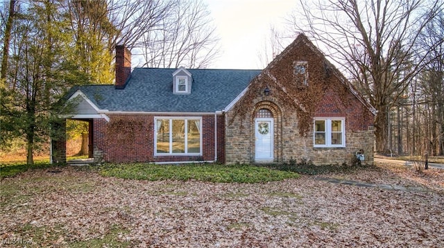 view of front of home featuring brick siding, a chimney, and a shingled roof