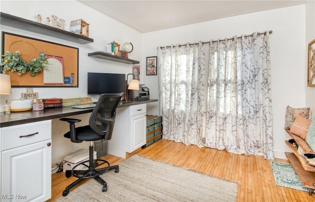 home office with light wood-type flooring and built in desk