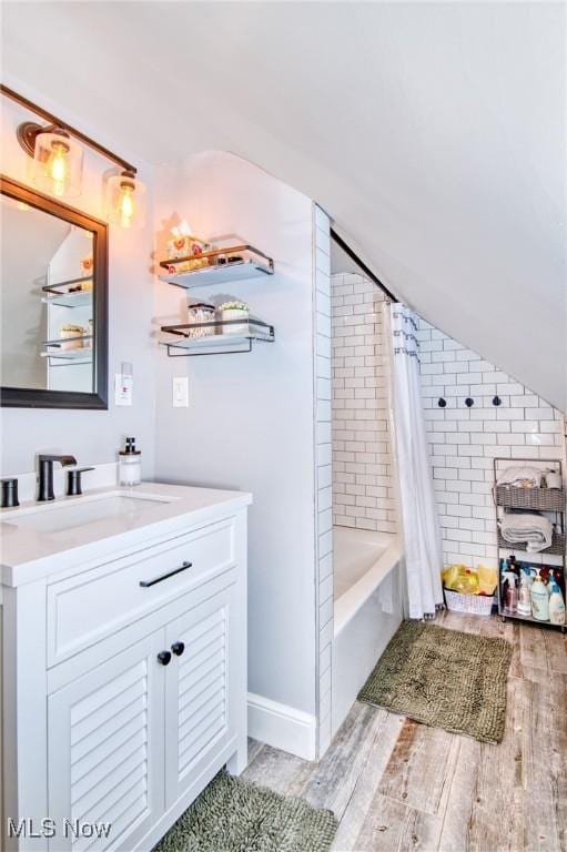 full bathroom featuring lofted ceiling, shower / tub combo, vanity, and wood finished floors