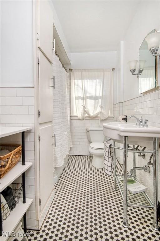 full bathroom with toilet, a wainscoted wall, and tile walls