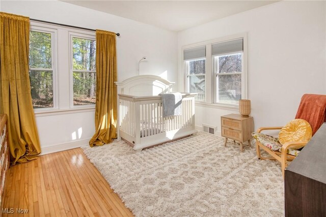 bedroom with wood-type flooring, visible vents, and baseboards