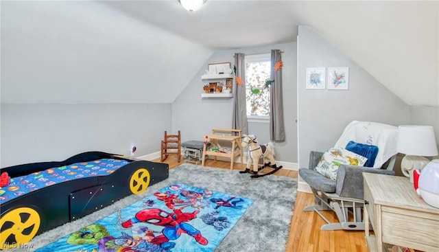 bedroom with lofted ceiling, baseboards, and wood finished floors