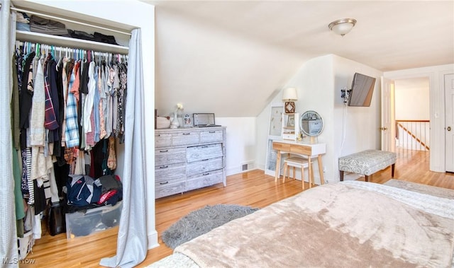 bedroom featuring a closet, visible vents, vaulted ceiling, and wood finished floors