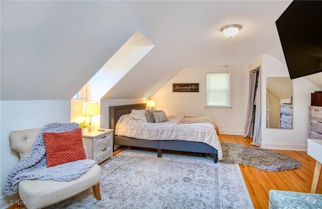 bedroom featuring lofted ceiling, baseboards, and wood finished floors