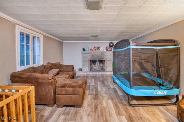 living room with a brick fireplace, crown molding, and wood finished floors